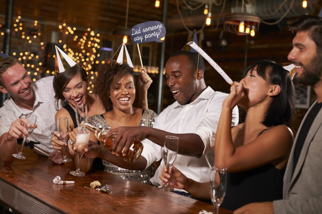 Friends pouring champagne at a New Year’s party at a bar